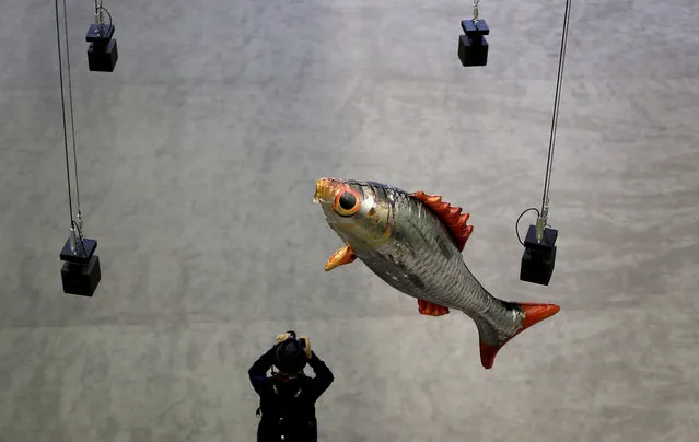 A photographer takes a picture as a fish balloon floats through hanging speakers, part of the new commission entitled “Anywhen” by French artist Philippe Parreno, in the Turbine Hall at the Tate Modern in London, Monday, October 3, 2016. The commission transforms the area into an experience that plays with time and space, and is open to the public from Oct. 4 until April 2, 2017. (Photo by Kirsty Wigglesworth/AP Photo)