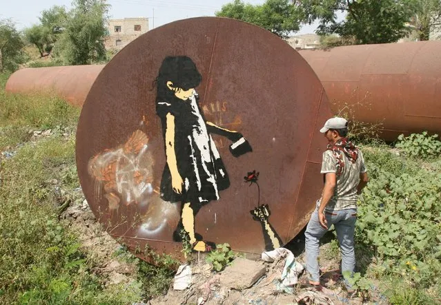 A man looks at a graffiti artwork painted by artist Murad Subay in Yemen's war-torn southwestern city of Taiz October 13, 2015. (Photo by Reuters/Stringer)