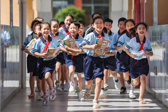 Students run with new books on hands in the campus of a primary school as new semester starts on September 1, 2025 in Hehzou, Guangxi Zhuang Autonomous Region of China. (Photo by Li Haotu/VCG via Getty Images)