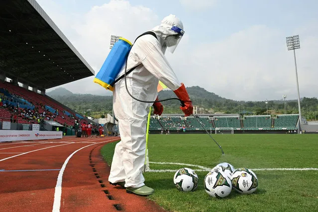 A technician disinfects official balls before the Group F Africa Cup of Nations (CAN) 2021 football match between Mauritania and Gambia at Limbe Omnisport Stadium in Limbe on January 12, 2022. (Photo by Issouf Sanogo/AFP Photo)