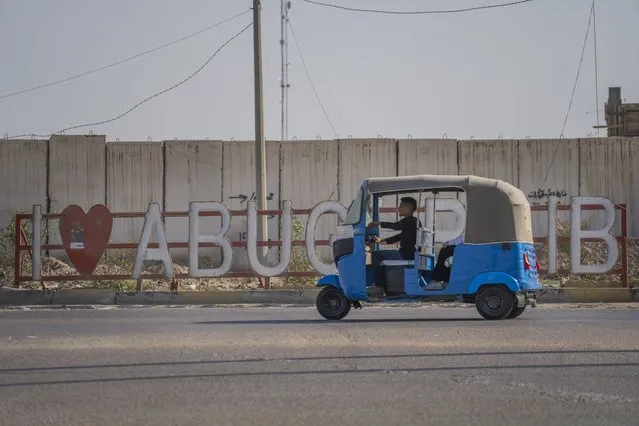 A motorized rickshaw, or tuk tuk, rides past the entrance of Abu Ghraib, Iraq, west of Baghdad, on Thursday, March 2, 2023. For Iraqis, the war and U.S. occupation which started two decades ago were traumatic – an estimated 300,000 Iraqis were killed between 2003 and 2019, according to an estimate by the Watson Institute for International and Public Affairs at Brown University, in addition to some 4,000 Americans. (Photo by Jerome Delay/AP Photo)