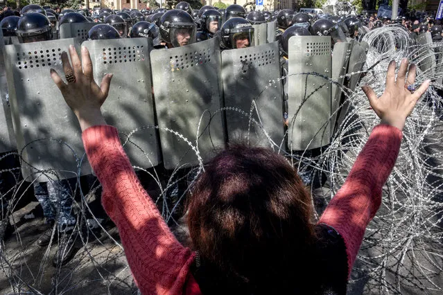A woman gestures as Armenian special police forces block a street during an opposition rally in central Yerevan on April 16, 2018. An opposition leader and several dozen other protesters were injured on April 16, 2018 in Armenia as thousands of people rallied against a move by the ex-president to maintain a chokehold on power. Police used stun grenades against protesters who sought to break through a barbed wire cordon in the centre of the capital Yerevan in an effort to get to the parliament building during rallies against former president Serzh Sarkisian. (Photo by Karen Minasyan/AFP Photo)