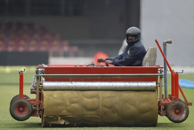 A worker operates a sponge-wrapped roller to dry the ground ahead of the second test cricket match between India and South Africa in Bengaluru, India, November 13, 2015. (Photo by Danish Siddiqui/Reuters)