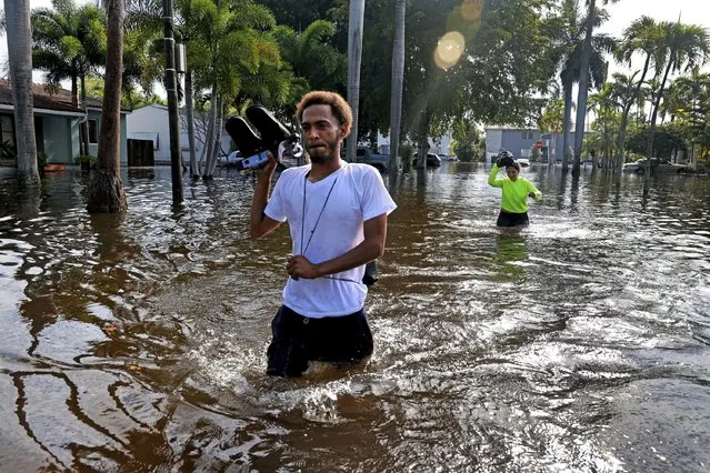 James Richard and Katherine Arroyo trudge through the water in Hollywood, Fla., on Thursday, April 13, 2023. South Florida has begun draining streets and otherwise cleaning up after an unprecedented storm that dumped upward of 2 feet of rain in a matter of hours. The rains caused widespread flooding, closed the Fort Lauderdale airport and turned thoroughfares into rivers. (Photo by Mike Stocker/South Florida Sun-Sentinel via AP Photo)