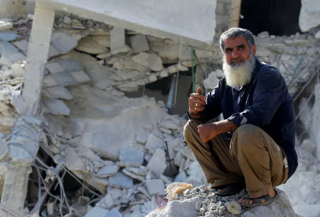 A man sits on the rubble of a damaged building at a site hit by overnight airstrikes in the town of Kafr Takharim, in Idlib Governorate, Syria October 24, 2016. (Photo by Ammar Abdullah/Reuters)