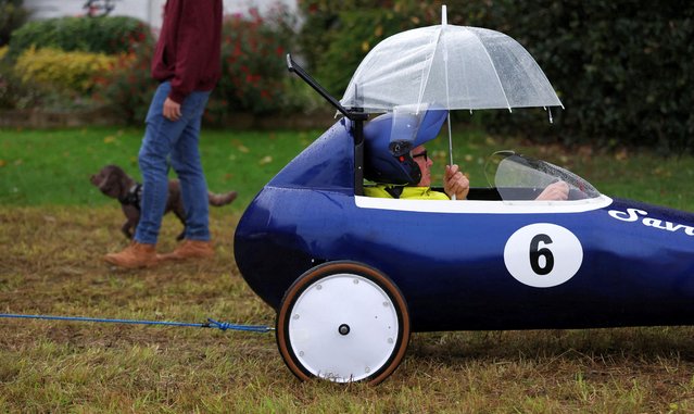 Contender James Savage holds an umbrella while waiting to be towed up the hill for the second round of the annual Gravity Grand Prix in Cookham Dean, Britain on September 14, 2025. (Photo by Suzanne Plunkett/Reuters)
