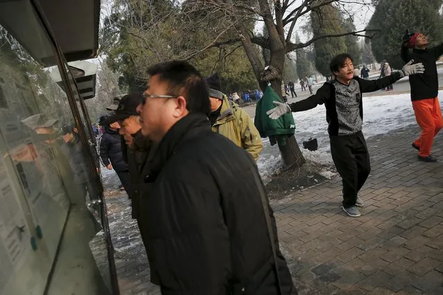 People exercise as others read newspapers displayed in a park on a heavily polluted morning in Beijing, China, November 29, 2015. Beijing plans to ramp up its already tough car emission standards by 2017 in a bid by one of the world's most polluted cities to improve its often hazardous air quality. (Photo by Damir Sagolj/Reuters)