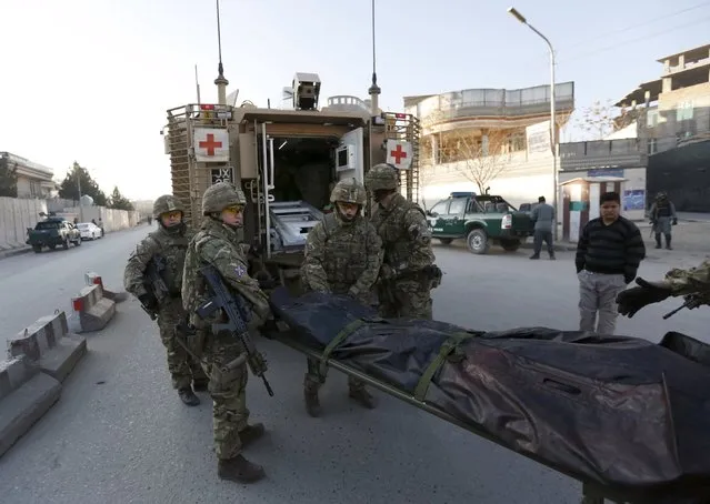 British soldiers carry the dead body of a victim after an attack on a guest house near the Spanish embassy in Kabul, Afghanistan December 12, 2015. Afghan security forces suppressed a suicide attack on a guest house attached to the Spanish embassy in Kabul, killing three Taliban fighters after hours of intermittent gunfire and explosions that lasted into the early hours of Saturday. (Photo by Mohammad Ismail/Reuters)