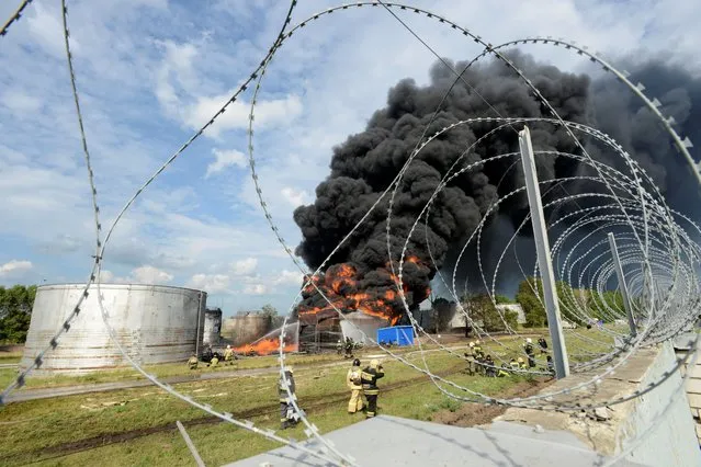 Emergencies ministry members work to extinguish fire at a burning fuel tank of an oil depot in Voronezh, Russia on June 24, 2023. (Photo by Reuters/Stringer)