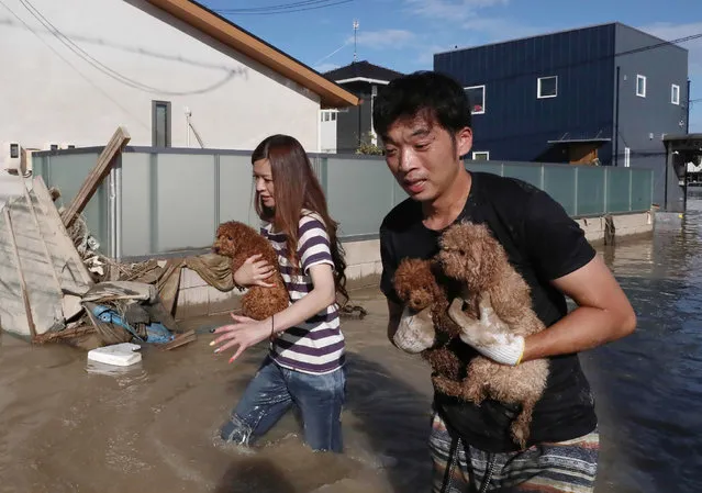 Residents rescue dogs from flooded area in Kurashiki, Okayama prefecture on July 8, 2018. The death toll from record rains that have devastated parts of Japan rose Sunday to at least 57, officials said, as rescue workers and troops struggled in the mud and water to save lives. (Photo by AFP Photo/JIJI Press/Stringer)