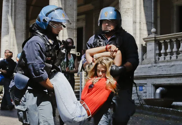 A protester is dragged away by Italian police outside the Ministry of Transport in Rome, Wednesday, July 11, 2018. Dozens of protesters chained themselves to the steps in a demonstration against the government's hard-line immigration policy. (Photo by Alessandra Tarantino/AP Photo)