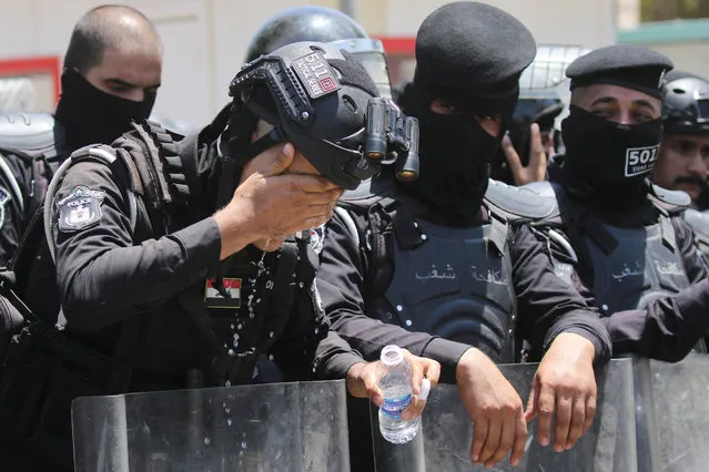 A police officer washes his face with water as protesters gather near the Turkish Embassy during a demonstration against cutting Iraq's water supply, in Baghdad, Iraq on July 18, 2023. (Photo by Ahmed Saad/Reuters)