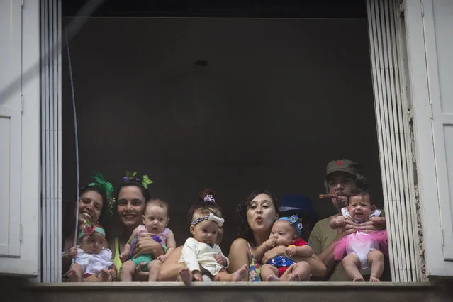 People and babies wearing carnival costumes watch the “Ceu na Terra”, or Heaven on earth, carnival parade from the window of a house in Rio de Janeiro, Brazil, Saturday, February 7, 2015. (Photo by Felipe Dana/AP Photo)