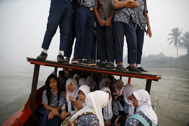 Students stand on the roof of a wooden boat as haze blankets the Musi River while they travel to school in Palembang, on Indonesia's Sumatra island, September 10, 2015. (Photo by Reuters/Beawiharta)