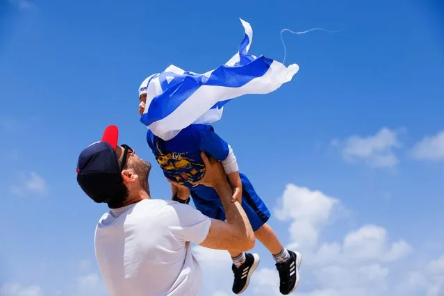 A man embraces a kid during celebrations for Israel's Independence Day, marking the 74th anniversary of the creation of the state, in Tel Aviv, Israel on May 5, 2022. (Photo by Amir Cohen/Reuters)