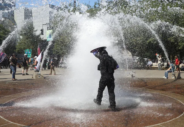 A right-wing supporter of the Patriot Prayer group cools off in a fountain during a rally in Portland, Ore., August  4, 2018. (Photo by Jim Urquhart/Reuters)