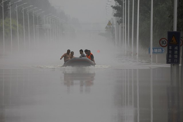 People ride a boat through a flooded road after the rains and floods brought by remnants of Typhoon Doksuri, in Zhuozhou, Hebei province, China on August 3, 2023. (Photo by Tingshu Wang/Reuters)