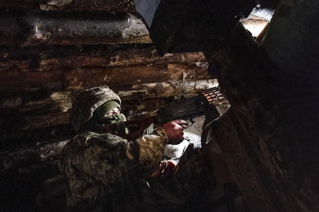 In this March 5, 2021, file photo, a Ukrainian serviceman keeps ready a machine gun in his shelter near the front-line town of Krasnohorivka, eastern Ukraine. Tensions are rising over the conflict in eastern Ukraine, with growing violations of a cease-fire and a massive Russian military buildup near its border with the region. (Photo by Evgeniy Maloletka/AP Photo/File)