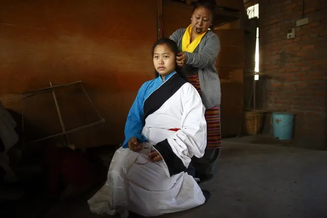 A woman helps a Tibetan girl who is dressed in traditional attire as she prepares to take part in a function organised to mark Losar or the Tibetan New Year at Tibetan Refugee Camp in Lalitpur February 19, 2015. (Photo by Navesh Chitrakar/Reuters)