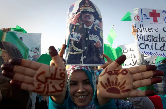 A woman shows script on her hand reading “I'll sacrifice my life for Muammar” during a rally in the Gaddafi hometown of Sirte, Libya, July 21, 2011. (Photo by Caren Firouz/Reuters)