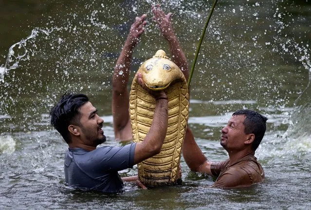 Nepalese devotees carry a golden statue of a snake “Nag” at Nagpokhari (Snake pond) in Bhaktapur, Nepal on August 21, 2023. Nepal observes the Nagpanchami, Snake Festival, to pray for protection from rain, landslides, floods and all natural calamities that occur during the monsoon season. (Photo by Narendra Shrestha/EPA/EFE)