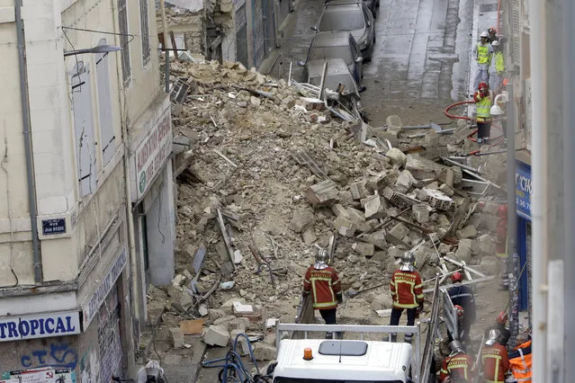 Firefighters work at the scene where buildings collapsed in Marseille, southern France, Monday, November 5, 2018.  Two buildings collapsed in the southern city of Marseille on Monday, leaving a giant pile of rubble and beams. Fire services said two people were lightly hurt. The collapse spewed debris into the street and clouds of dust into the air, and left a big gap where the two buildings used to be. (Photo by Claude Paris/AP Photo)