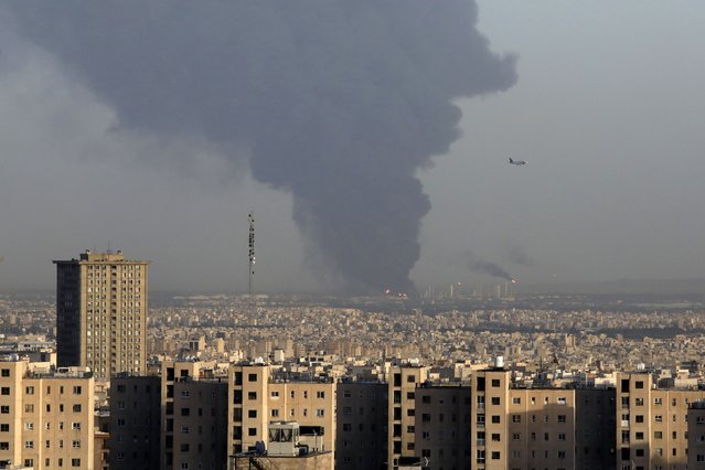 Huge smoke rises up from Tehran's main oil refinery as a plane approaches Mehrabad airport south of Tehran, Iran, Wednesday, June 2, 2021. A massive fire broke out Wednesday night at the oil refinery serving Iran's capital, sending thick plumes of black smoke over Tehran. (Photo by Vahid Salemi/AP Photo)