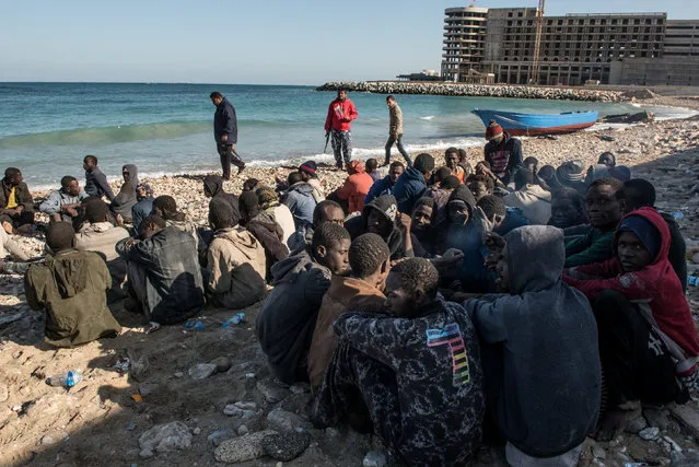 Migrants, who were on a boat which capsized on Wednesday, sit on a beach after policemen arrested them in Tripoli, Libya, January 4, 2017. (Photo by Reuters/Stringer)