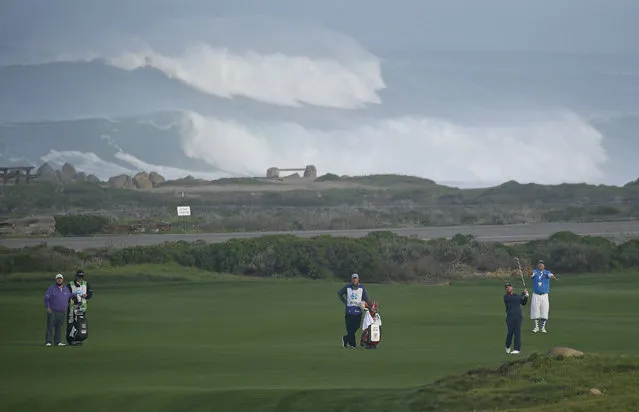 Scott Brown, right, follows his shot from the 10th fairway of the Monterey Peninsula Country Club Shore Course, with large waves in the background, during the second round of the AT&T Pebble Beach National Pro-Am golf tournament Friday, February 12, 2016, in Pebble Beach, Calif. At left is Brown's playing partner Colt Ford. (Photo by Eric Risberg/AP Photo)