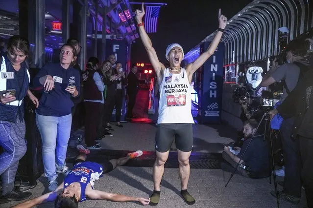 Malaysia's Wai Ching Soh, center, screams victorious after taking a win over second place finisher, Japan's Ryoii Watanabe Ryoji, left, who lies on the ground exhausted, in the 44th Annual Empire State Building Run-Up, Thursday October 6, 2022, in New York. (Photo by Bebeto Matthews/AP Photo)
