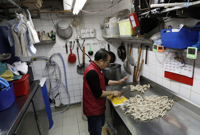 In this Monday, January 23, 2017 photo, chicken feet snacks shop owner Leung Kin-kung chops off chicken feets in Hong Kong. (Photo by Vincent Yu/AP Photo)
