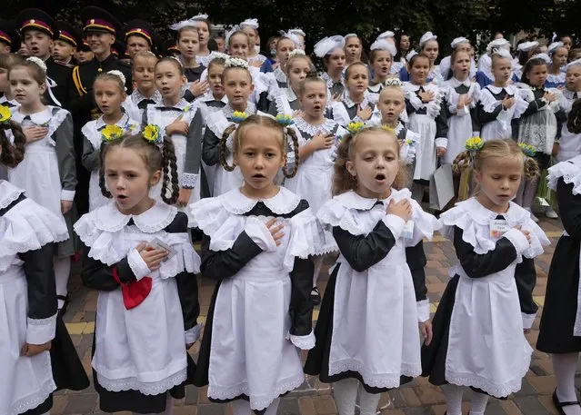 Schoolgirls in traditional uniforms, sing Ukraine's national anthem as they attend a ceremony of the first day in school at a cadet lyceum in Kyiv, Ukraine, Wednesday, September 1, 2021. Ukraine marks Sept. 1 as Knowledge Day, as a traditional launch of the academic year. (Photo by Efrem Lukatsky/AP Photo)