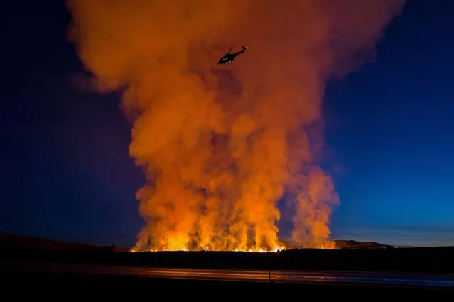 A helicopter flies near smoke rising as a volcano erupts in Grindavik, Iceland, on January 14, 2024. (Photo by Icelandic Coast Guard/Handout via Reuters)