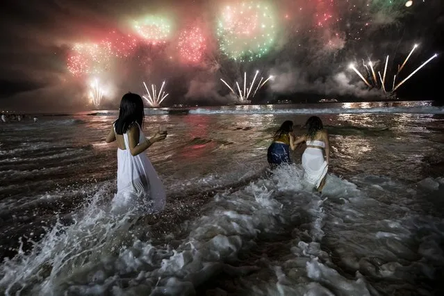 People bring in the New Year as they watch fireworks explode over Copacabana Beach in Rio de Janeiro, Brazil, early Sunday, January 1, 2023. (Photo by Bruna Prado/AP Photo)