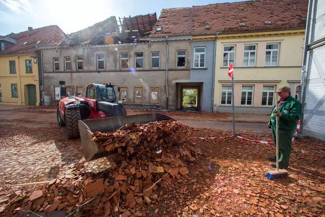 Fire fighters and helpers clear debris using heavy-duty vehicles, a day after a heavy storm in the town of Buetzow, Germany, 06 May 2015. A heavy storm caused substantial damage in northern Germany on 05 May. (Photo by Jens Buettner/EPA)