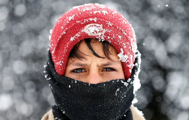 An Internally displaced Afghan boy looks on as he stands outside his shelter during a snowfall in Kabul, Afghanistan February 5, 2017. (Photo by Mohammad Ismail/Reuters)