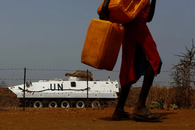 An internally displaced woman carries empty jerrycans as she walks past a United Nations armoured vehicle in a United Nations Mission in South Sudan (UNMISS) Protection of Civilian site (CoP), outside Juba, South Sudan, January 28, 2017. (Photo by Siegfried Modola/Reuters)