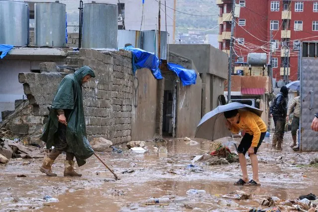 People clean after the floods that swept the city due to the heavy rain, in Duhok, Iraq on March 19, 2024. (Photo by Ari Jalal/Reuters)