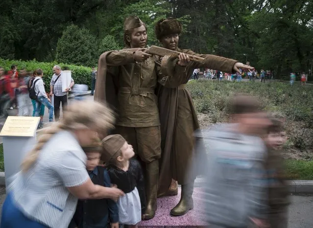 People walk past artists depicting World War Two Soviet soldiers, during Victory Day commemorations in Almaty, Kazakhstan, May 9, 2015. (Photo by Shamil Zhumatov/Reuters)