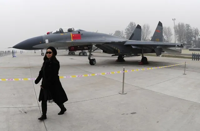 In this November 8, 2009, file photo, a woman walks near a Chinese People's Liberation Army Air Force's J-11 fighter jet displayed for the Air Force's 60th anniversary at an airport in Beijing, China. Taiwan says its planes warned off Chinese military aircraft that crossed the center line in the Taiwan Strait, calling China’s move a provocation that seeks to alter the status quo in the waterway dividing the island from mainland China. (Photo by AP Photo/File)
