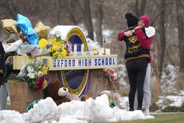 Students hug at a memorial at Oxford High School in Oxford, Mich., Wednesday, December 1, 2021. Authorities say a 15-year-old sophomore opened fire at Oxford High School, killing four students and wounding seven other people on Tuesday. (Photo by Paul Sancya/AP Photo)