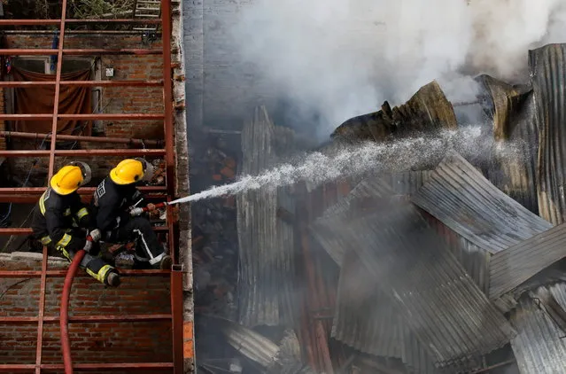 Firefighters work to douse a fire in a warehouse where blankets were stored in Kathmandu, Nepal on December 3, 2021. (Photo by Navesh Chitrakar/Reuters)