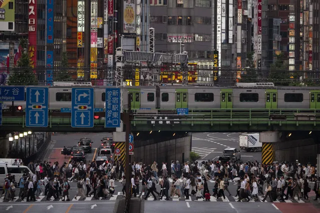 A large crowd passes a pedestrian crossing as a commuter train travels overhead Monday, May 27, 2019, in the Shinjuku district of Tokyo. (Photo by Jae C. Hong/AP Photo)