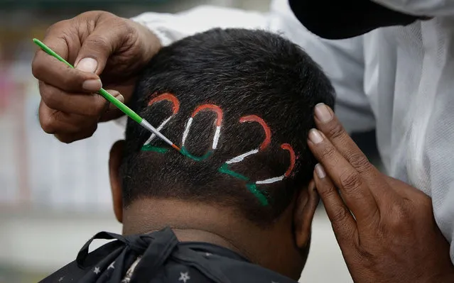 A barber colours the digits of the number 2022 after cutting a man's hair to welcome the upcoming new year, at a barbershop in Ahmedabad, India, December 31, 2021. (Photo by Amit Dave/Reuters)