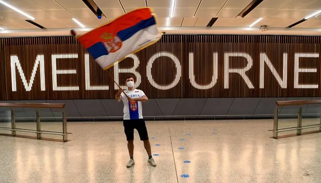 A Serbian tennis fan waves a flag as he awaits the arrival of Serbia's tennis champion Novak Djokovic in Melbourne on January 6, 2022. After arriving in Melbourne late on January 5, world number one Novak Djokovic may have encountered a late snag on his trip to play in the Australian Open, after state government officials refused to support his visa application. (Photo by William West/AFP Photo)