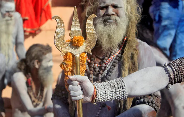 A Hindu holy man looks on as another holds a trident after taking a dip in the waters of the river Shipra during the Simhastha Kumbh Mela in Ujjain, India, April 22, 2016. (Photo by Jitendra Prakash/Reuters)