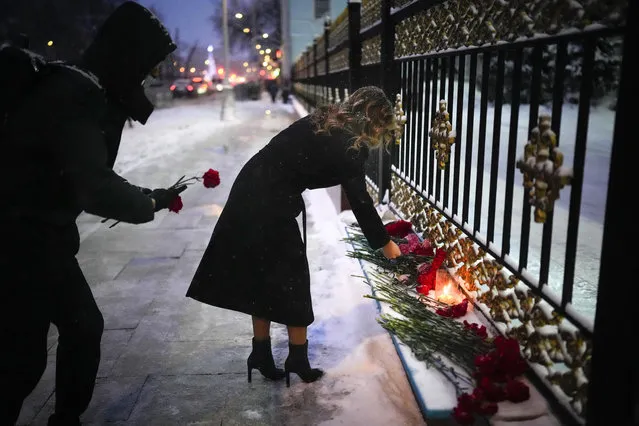 People lay lay flowers in memory of victims during at the fence of the Kazakhstan Embassy in Moscow, Russia, Monday, January 10, 2022. The authorities in Kazakhstan said Monday that nearly 8,000 people were detained by police during protests that descended into violence last week and marked the worst unrest the former Soviet nation has faced since gaining independence 30 years ago. (Photo by Alexander Zemlianichenko/AP Photo)
