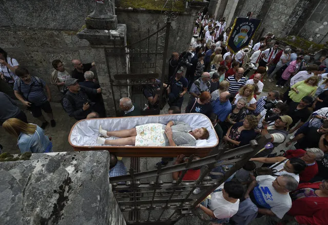 A woman is carried in a coffin by relatives during the annual “Procession of the Shrouds” to celebrate Saint Martha “the Saint of resurrection” in the village of Santa Marta de Ribarteme, northwestern Spain, near Nieves, on July 29, 2019. People who have escaped death lie in caskets and are carried in procession by relatives in a thankful gesture for being kept alive. (Photo by Miguel Riopa/AFP Photo)
