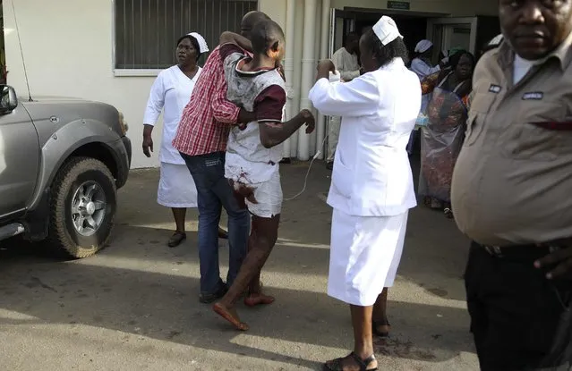 People help the victim of a bomb blast at the Asokoro General Hospital in Abuja, April 14, 2014. (Photo by Afolabi Sotunde/Reuters)