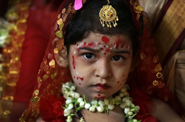 A young girl yet to attain puberty is dressed up as living goddess before being worshipped as “kumari” or virgin during the Bengali Hindu festival of Basanti Durga puja performed in the spring in Kolkata, India, Friday, April 15, 2016. Worshipping kumaris or virgins on the ninth day or navami of the festival is an important ritual when they are worshipped as the base power of all creation. The more popular form of Durga festival is performed in autumn when the Hindu mythical figure Rama is said to have called upon goddess Durga to seek her blessings to defeat the evil character Ravana. (Photo by Bikas Das/AP Photo)